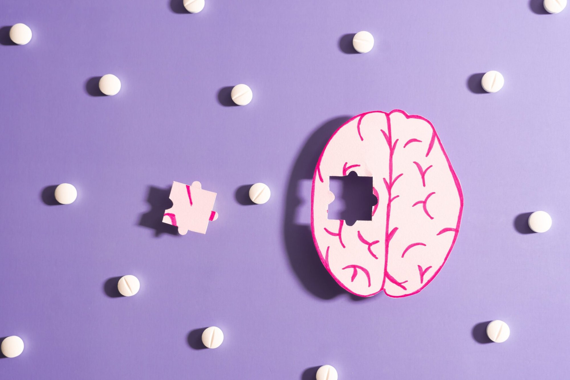 Illustration-of-human-brain-on-purple-background-puzzle-piece-missing-surrounded-by-pills-2048x1365